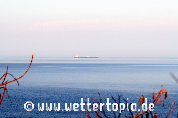 Glatte Ostsee mit kleinen Wellen im Vordergrund vor Warnemünde